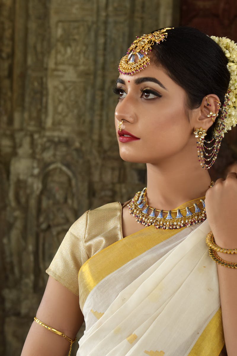 Beautiful Indian woman in traditional saree, adorned with exquisite jewelry, set against historic architecture.