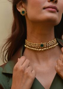Home Close-up of a woman wearing a stylish gold and emerald jewelry set.